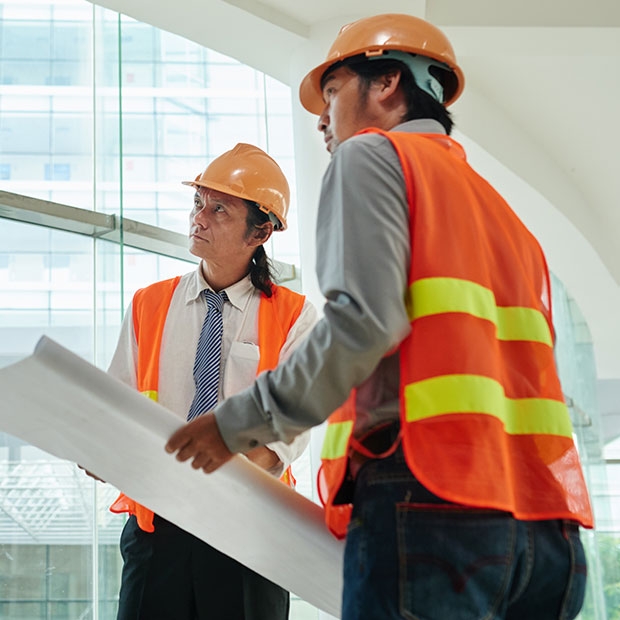 Indian project managers reviewing architectural blueprints at a construction site