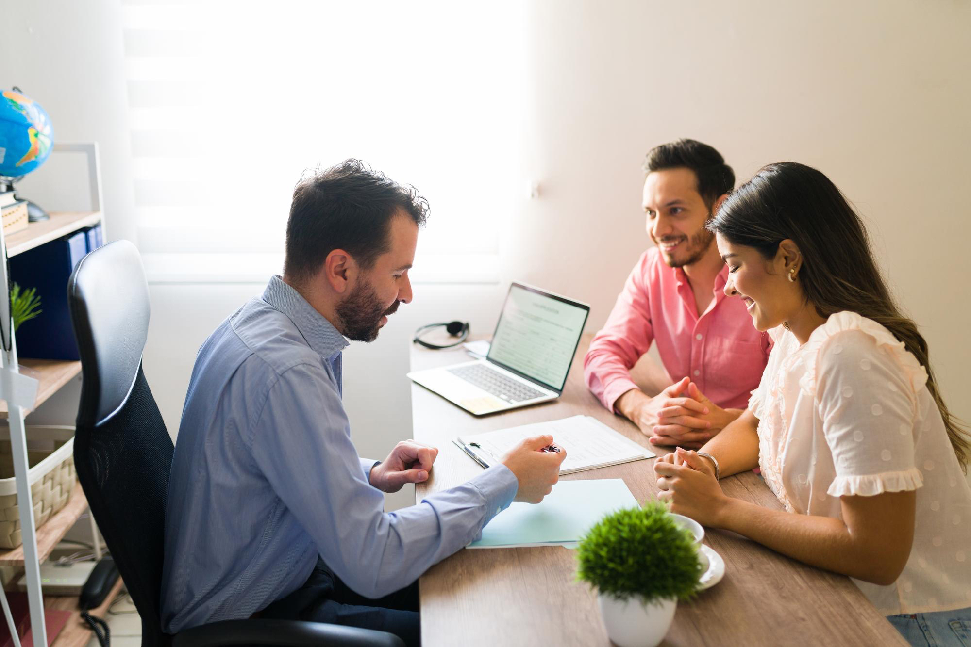 Indian real estate advisor discussing property plans with a young couple in a professional office